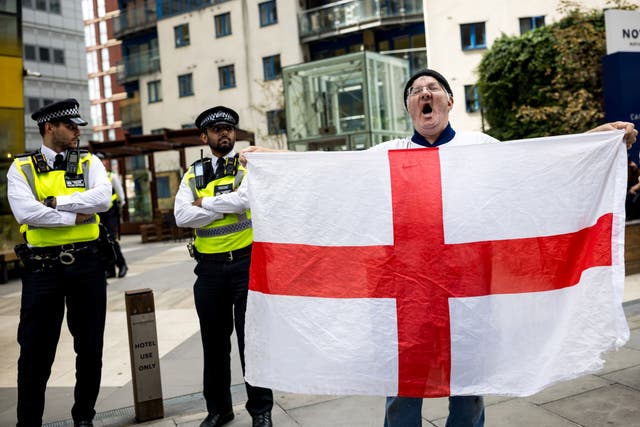 <p>A man holds an England flag and shouts at protesters attending a rally organised by Stand Up To Racism in London</p>