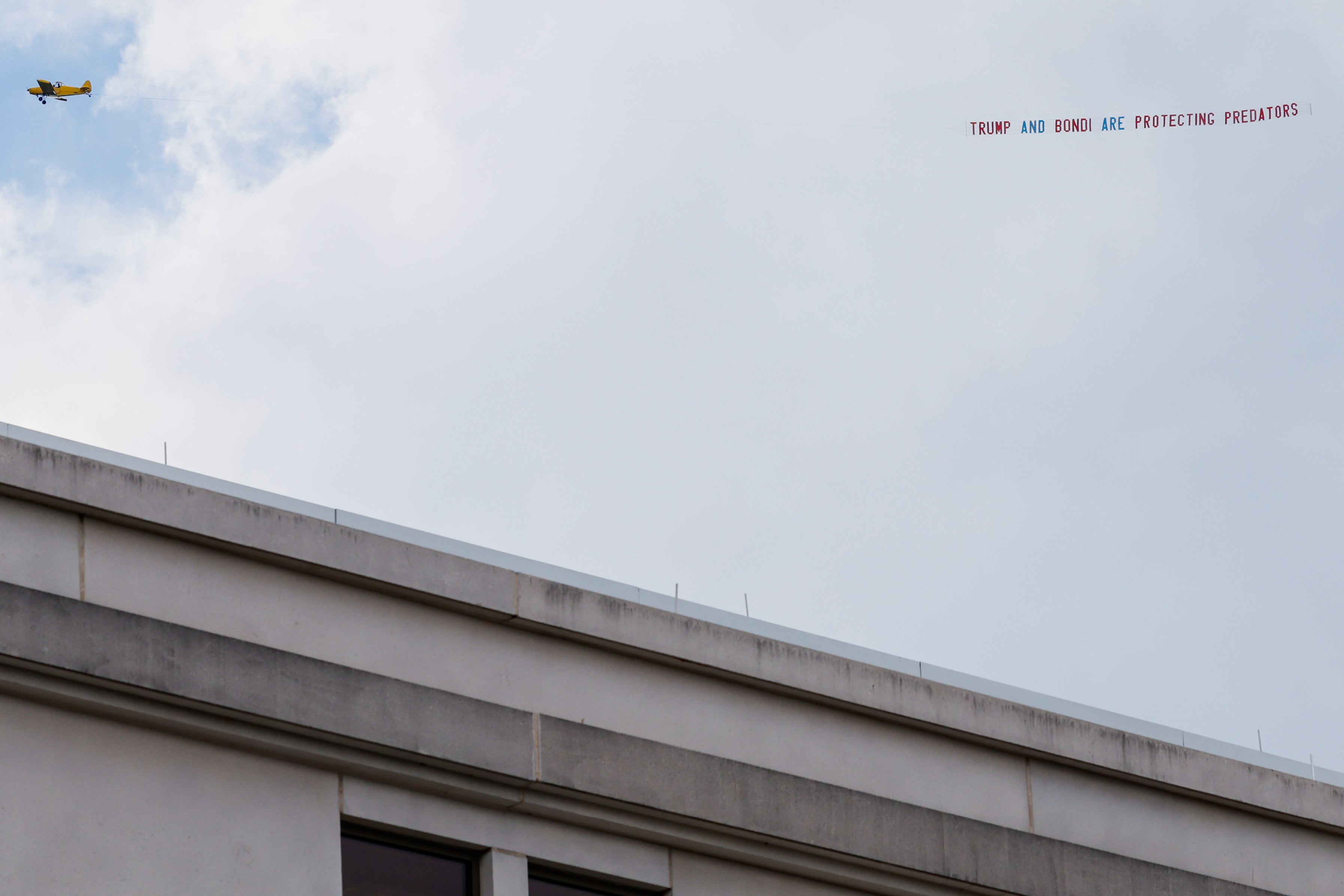 An airplane towing a banner that reads 'Trump and Bondi are protecting predators' is seen over the federal courthouse in Tallahassee, Florida, on Friday, July 25, 2025