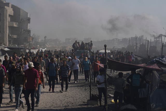 Palestinians walk along a road towards an area in the northern Gaza Strip where trucks are entering with humanitarian aid in Gaza City (Abdel Kareem Hana/AP)