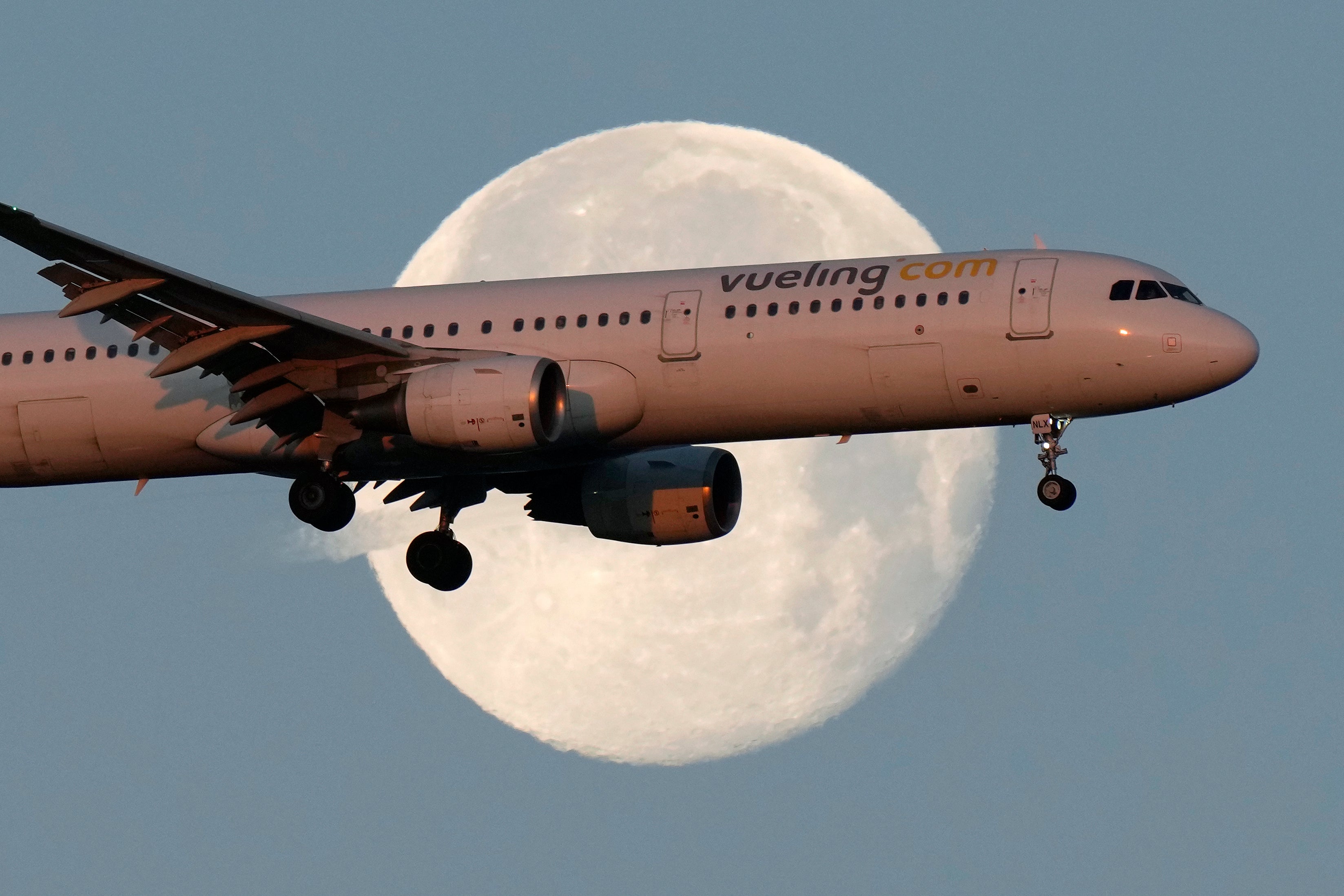 A Vueling Airbus A321 approaches for landing in Lisbon at sunrise, while the moon sets in the background,, Feb. 7, 2023. (AP Photo/Armando Franca, File)
