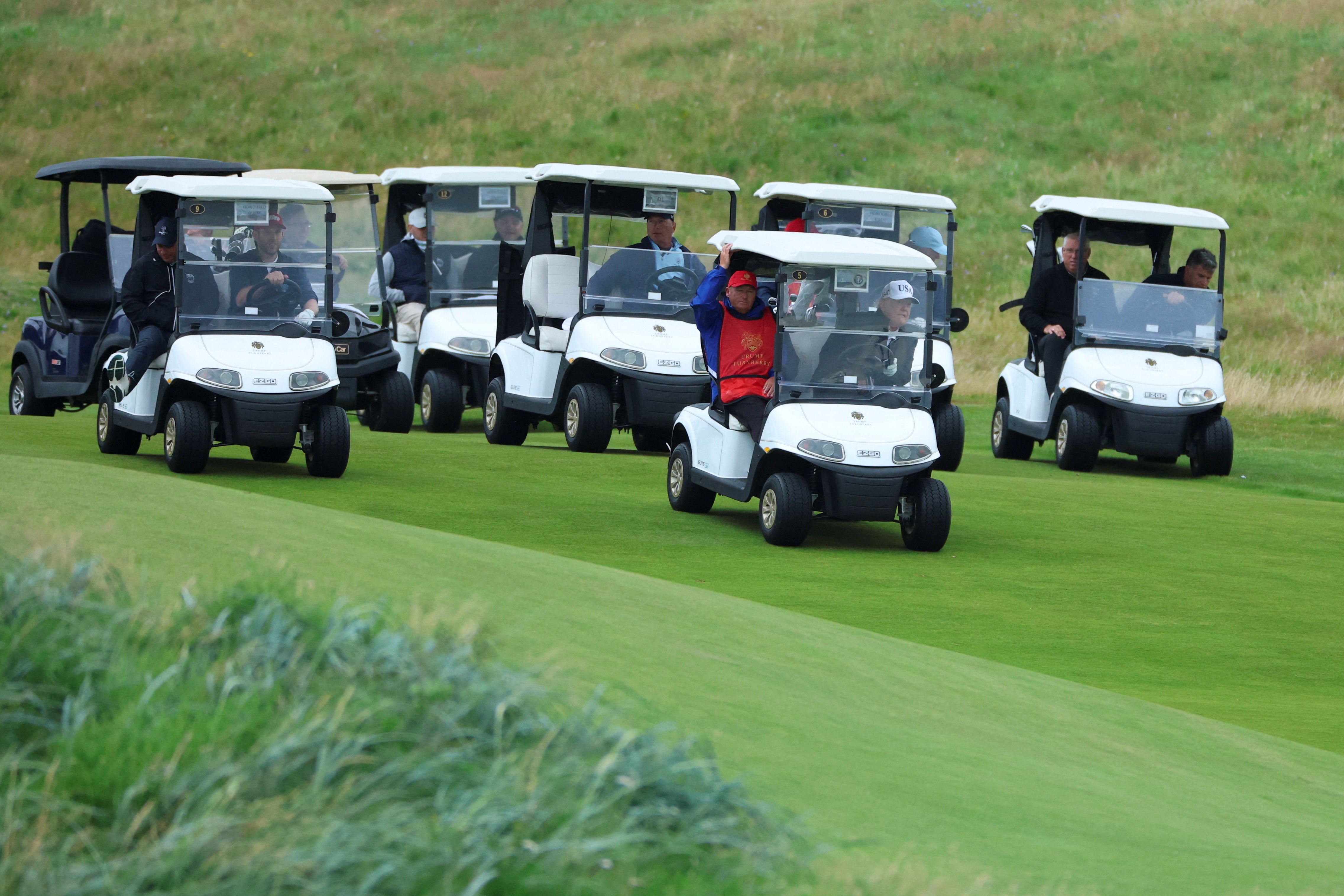 Wearing a white baseball cap branded USA, the US President waved the journalists as he arrived at his turnberry golf resort in a white golf buggy