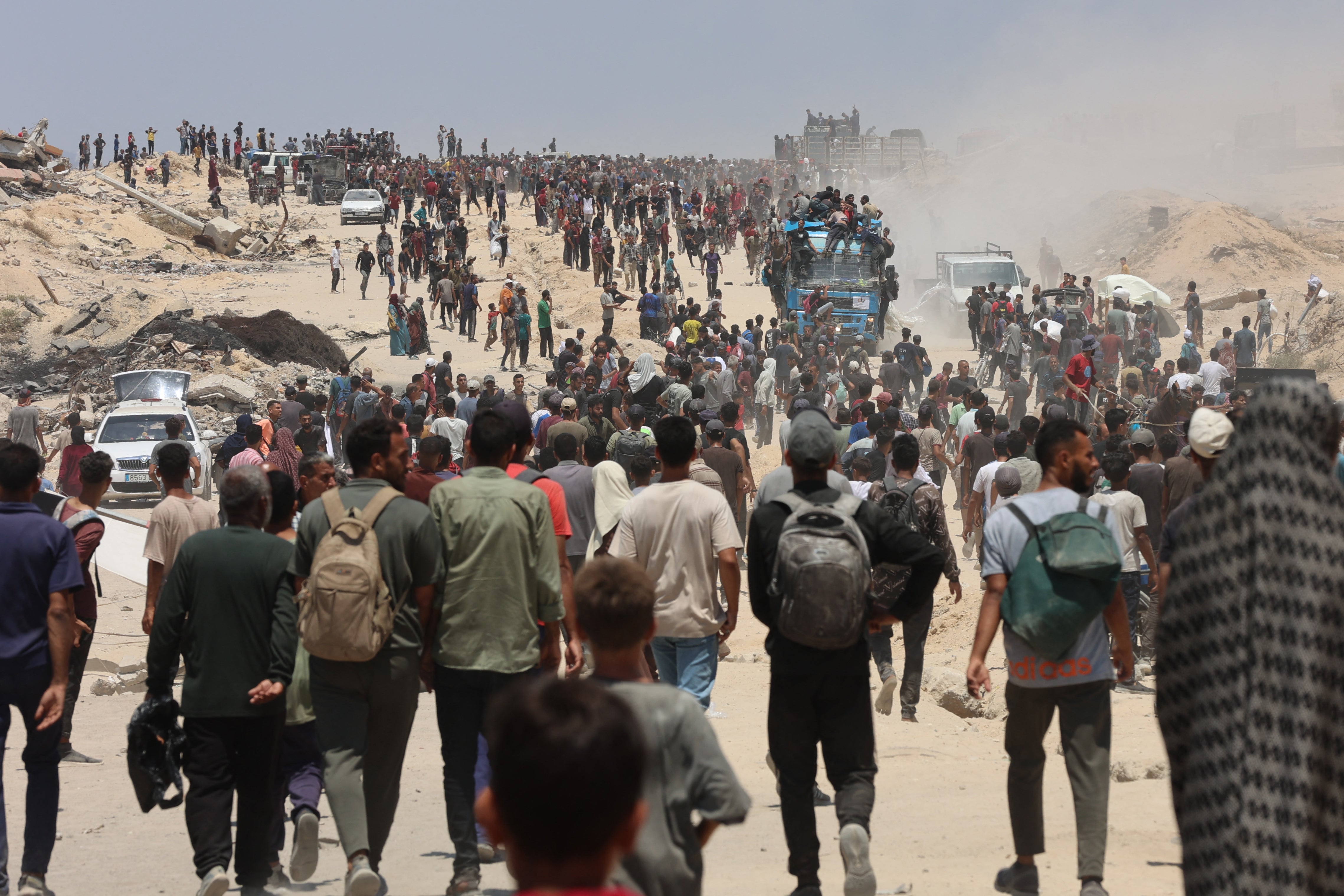 People make their way along al-Rashid street in western Jabalia on July 22, 2025, towards trucks carrying humanitarian aid