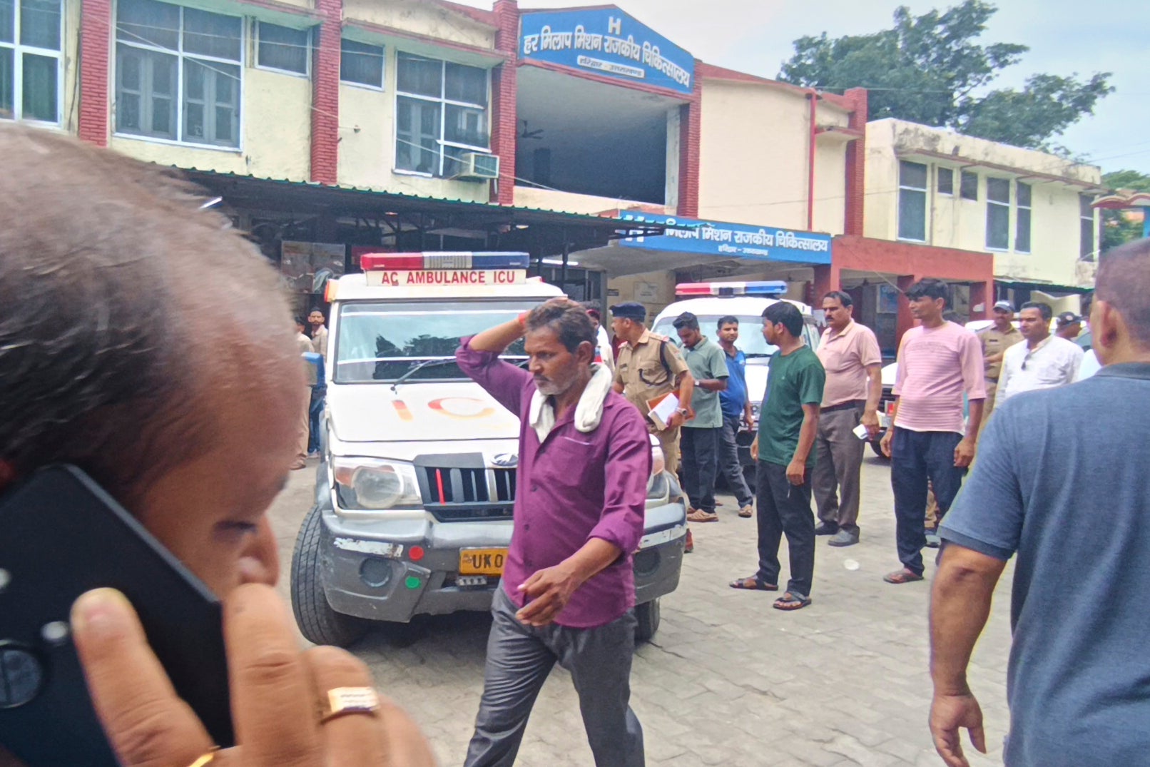 Relatives stand outside a hospital as the injured from temple stampede were brought, in Haridwar, India