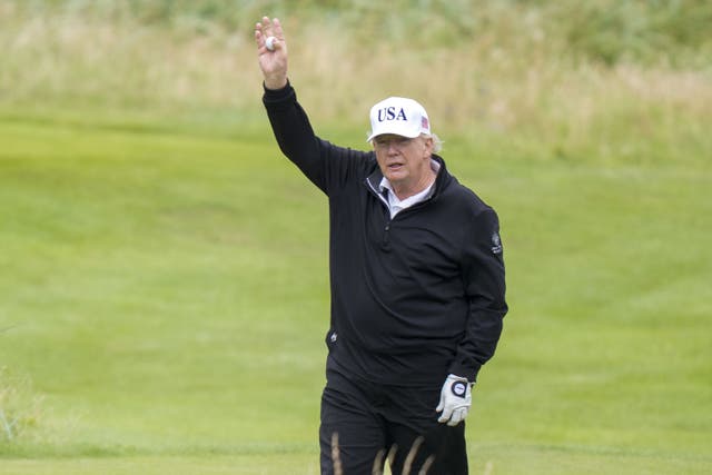 Donald Trump waves as he plays golf (Jane Barlow/PA)