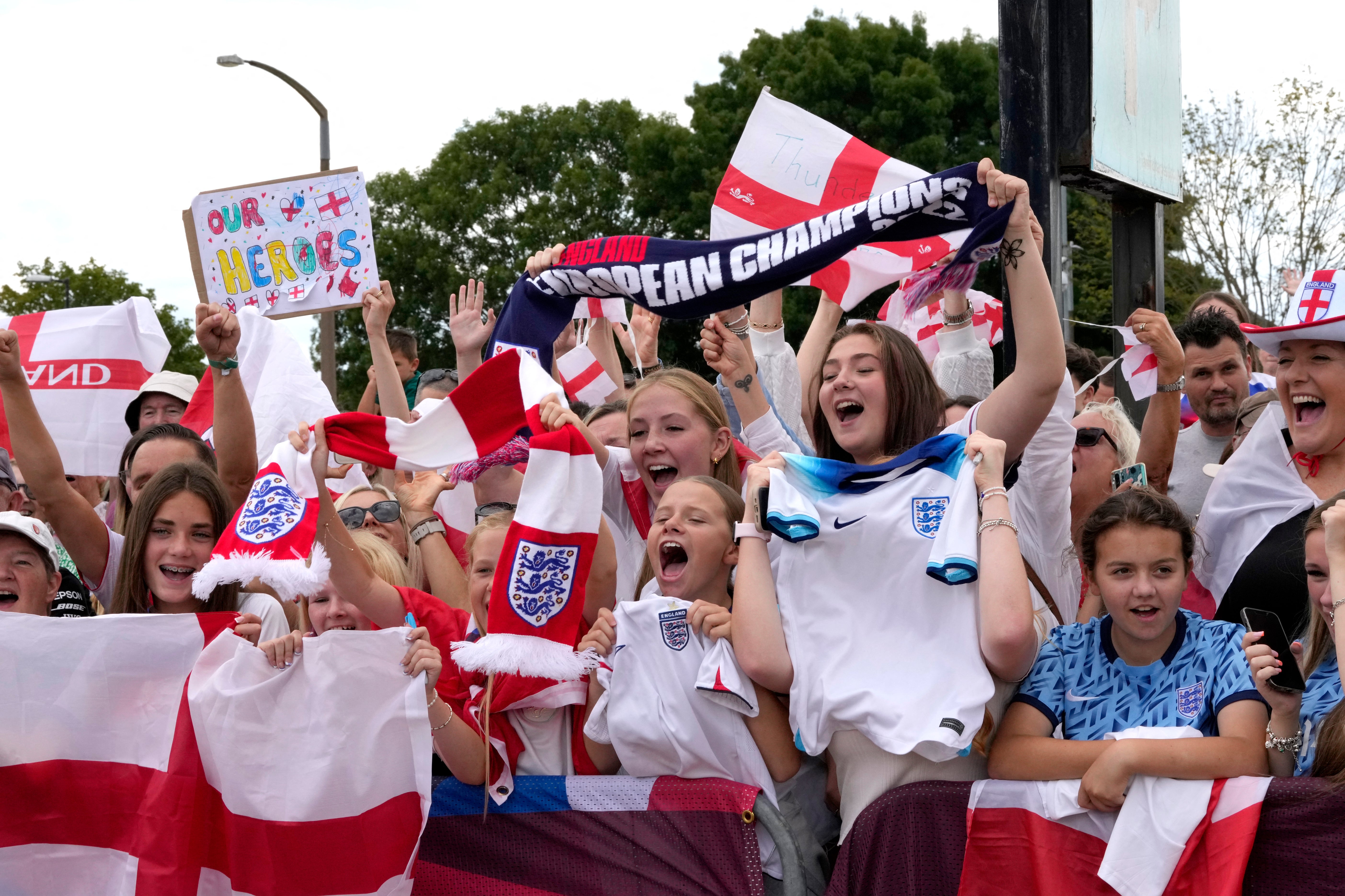 Fans wait with banners and flags to welcome the England Women's national football team at Southend Airport