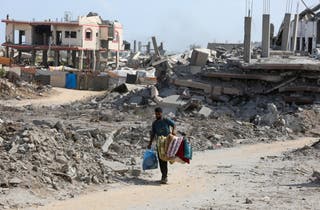 A Palestinian man walks near the rubble of houses destroyed during an Israeli raid, in western part of Nuseirat, central Gaza Strip