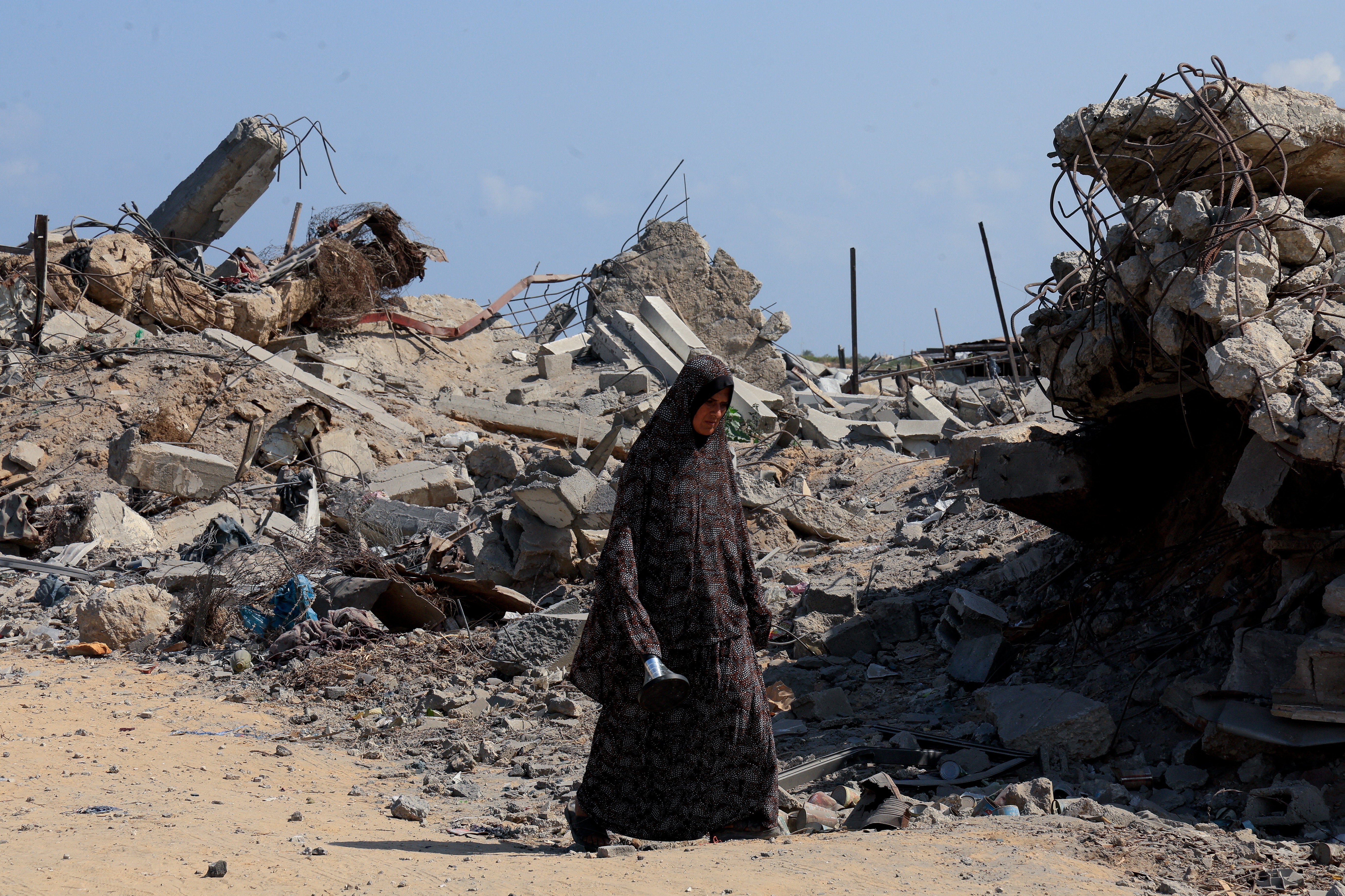 A Palestinian woman walks at the site of houses destroyed during an Israeli raid in the western part of Nuseirat, central Gaza Strip, on Tuesday