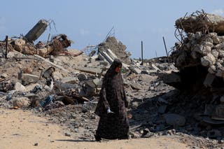 A Palestinian woman walks at the site of houses destroyed during an Israeli raid, in western part of Nuseirat, central Gaza Strip