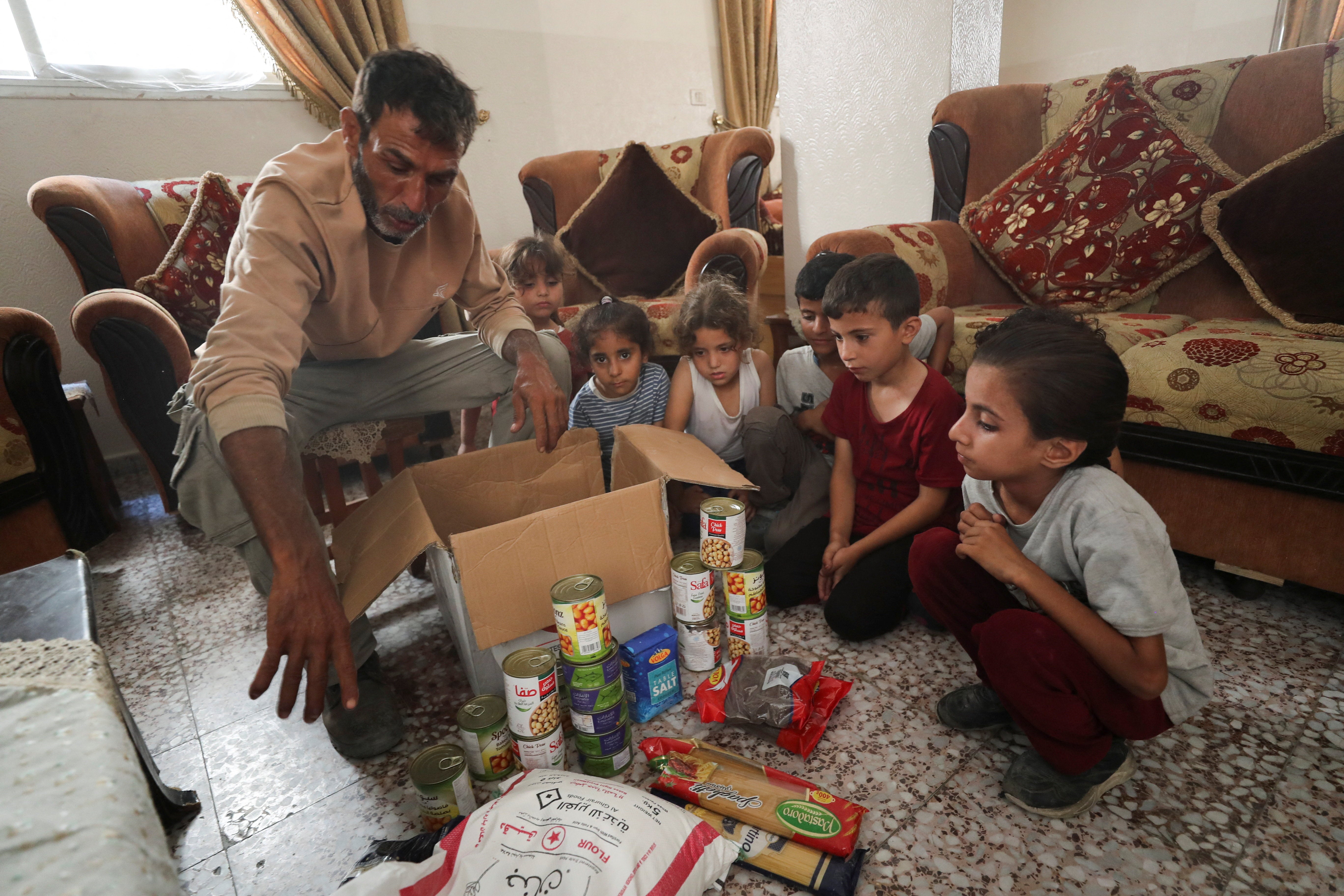 Fares Zaher, a Palestinian father of eight, displays the contents of an airdropped food parcel he received, in Gaza City