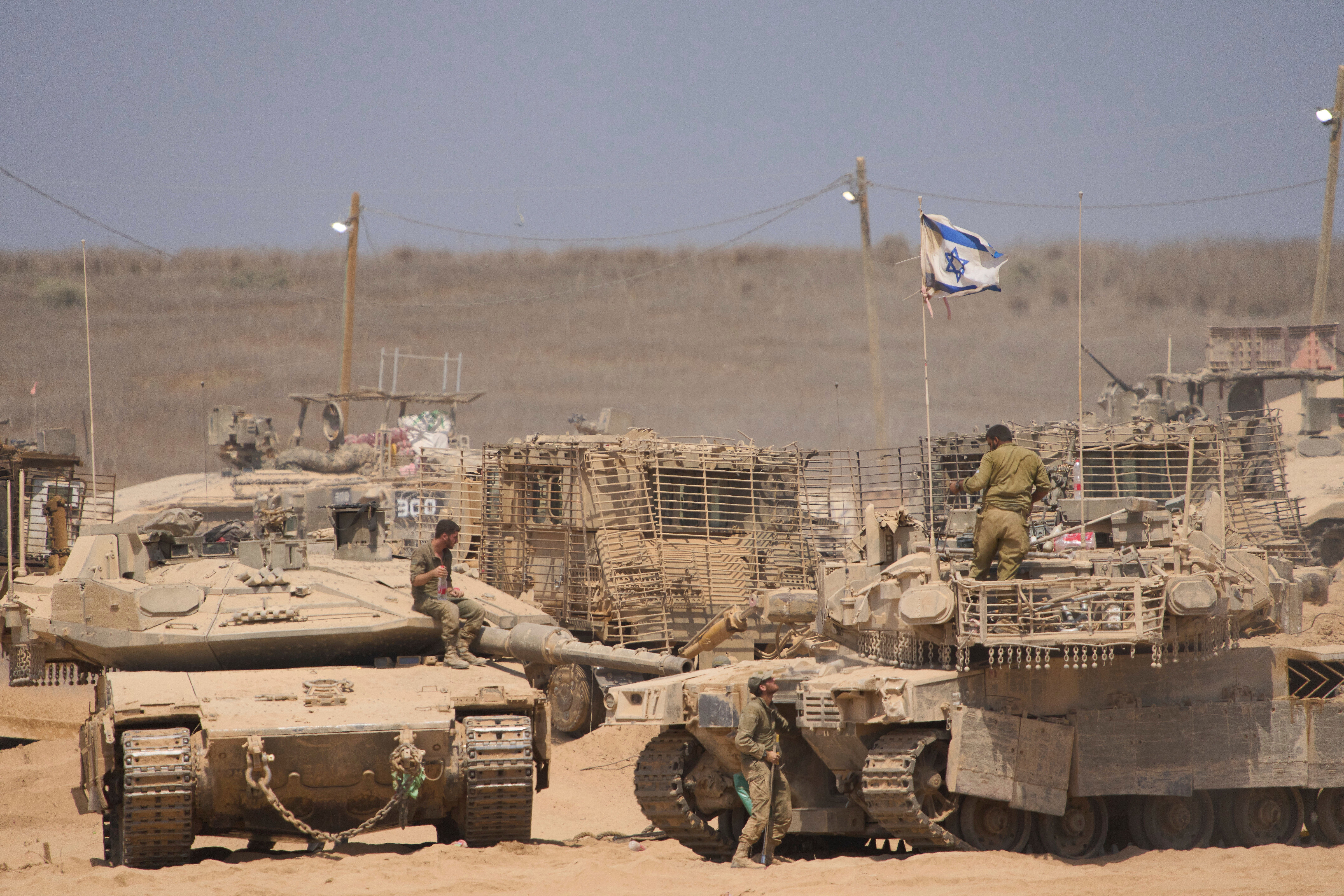 Israeli soldiers work on their tanks in a staging area on the border with Gaza Strip in southern Israel on Tuesday