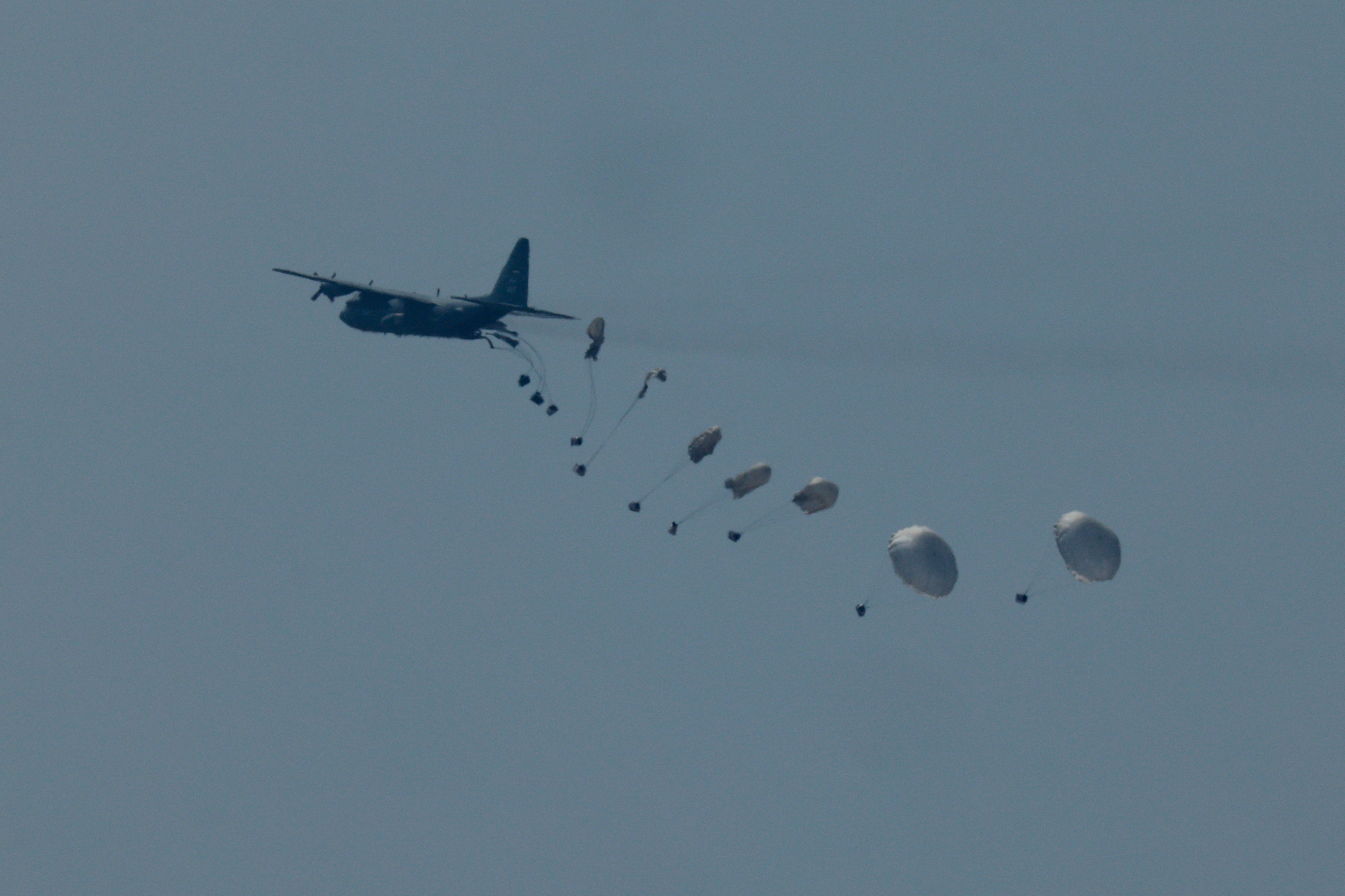 An aircraft drops humanitarian aid packages over the Gaza Strip, as seen from Israel