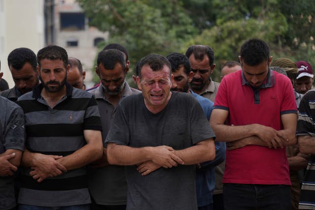 <p>A group of Palestinians pray next to the body of a person killed while trying to reach aid trucks entering northern Gaza through the Zikim crossing with Israel</p>