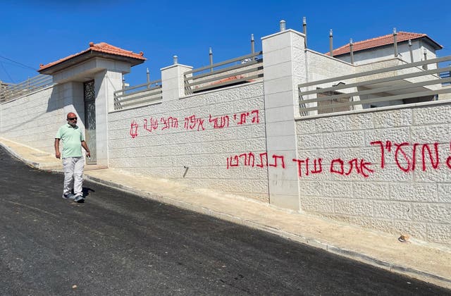 <p>A Palestinian man walks next to a wall covered with sprayed Hebrew slogans following an Israeli settler attack in Taybeh near Ramallah, in occupied West Bank, on 28 July 2025</p>