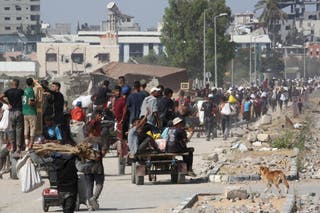 Displaced Palestinians at the Nuseirat refugee camp haul food parcels and other items they managed to get from a GHF aid distribution point at the so-called 