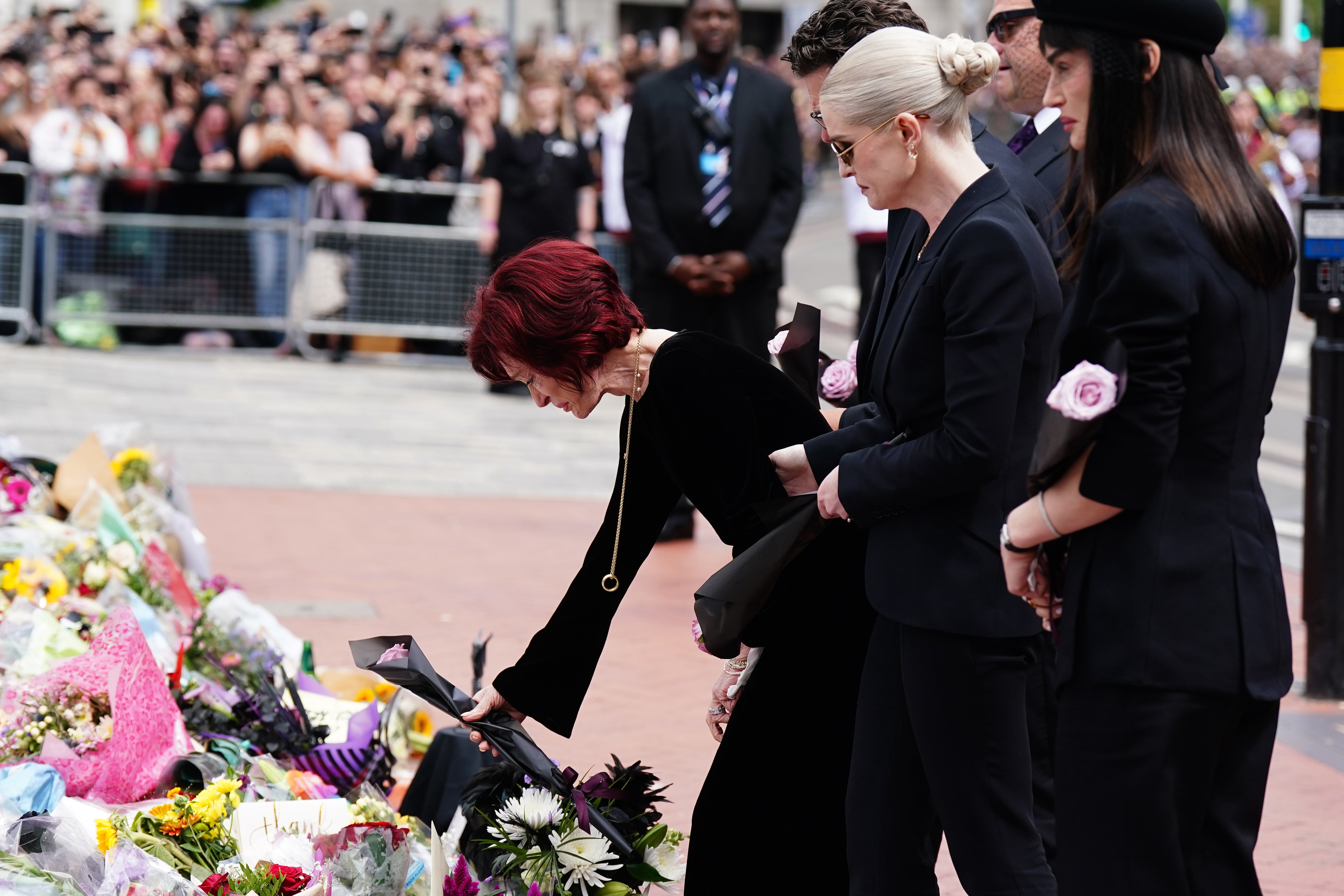 Sharon Osbourne and other family members lay flowers and view messages and floral tributes left at the Black Sabbath Bridge bench on Broad Street in Birmingham