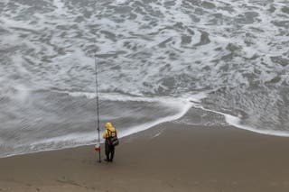 A a fisherman stands by the Ocean Beach, California, after authorities warned residents of the possibility of tsunami waves