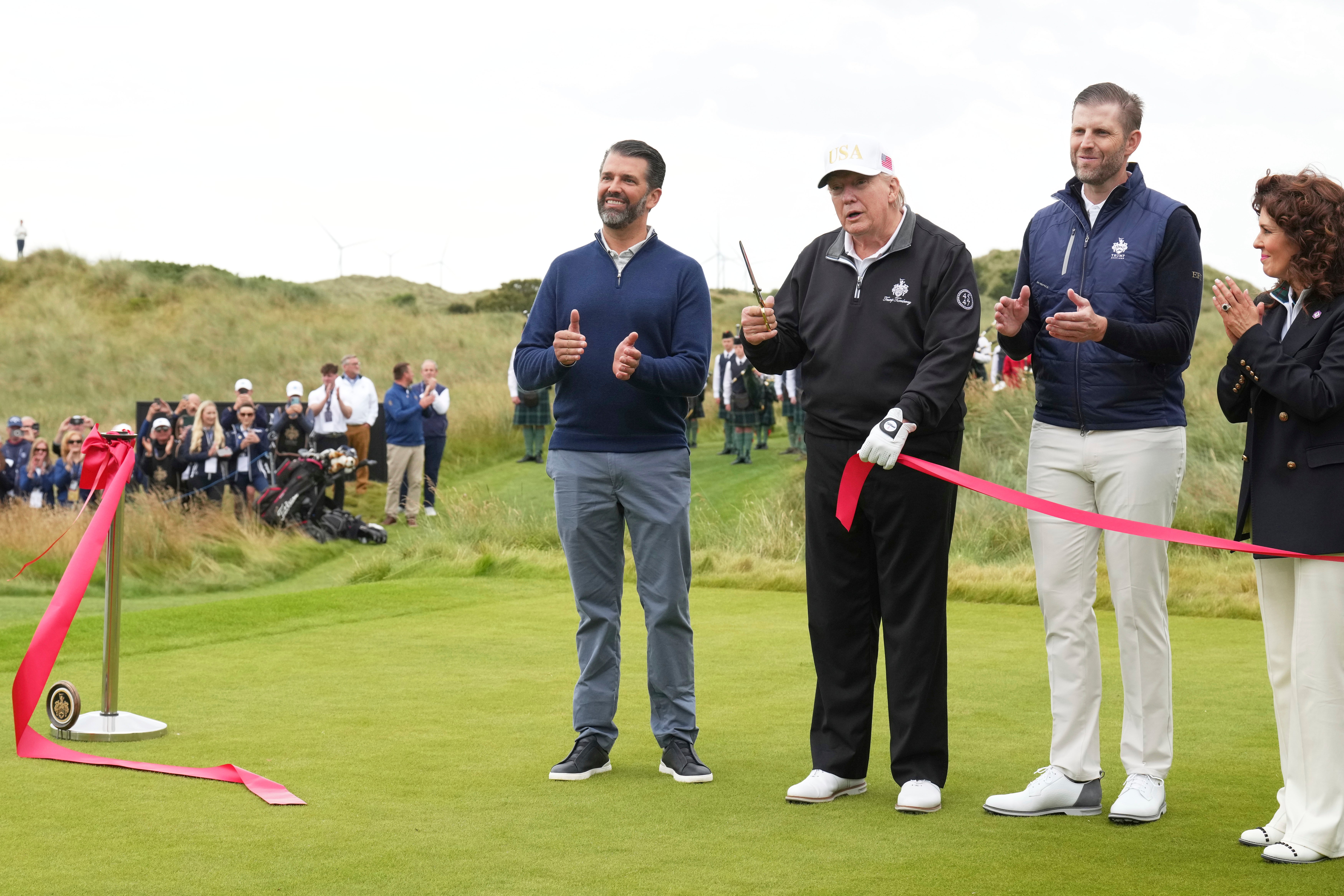 President Donald Trump holds scissors after cutting the inaugural ribbon during an opening ceremony for the Trump International Golf Links golf course near Aberdeen, Scotland