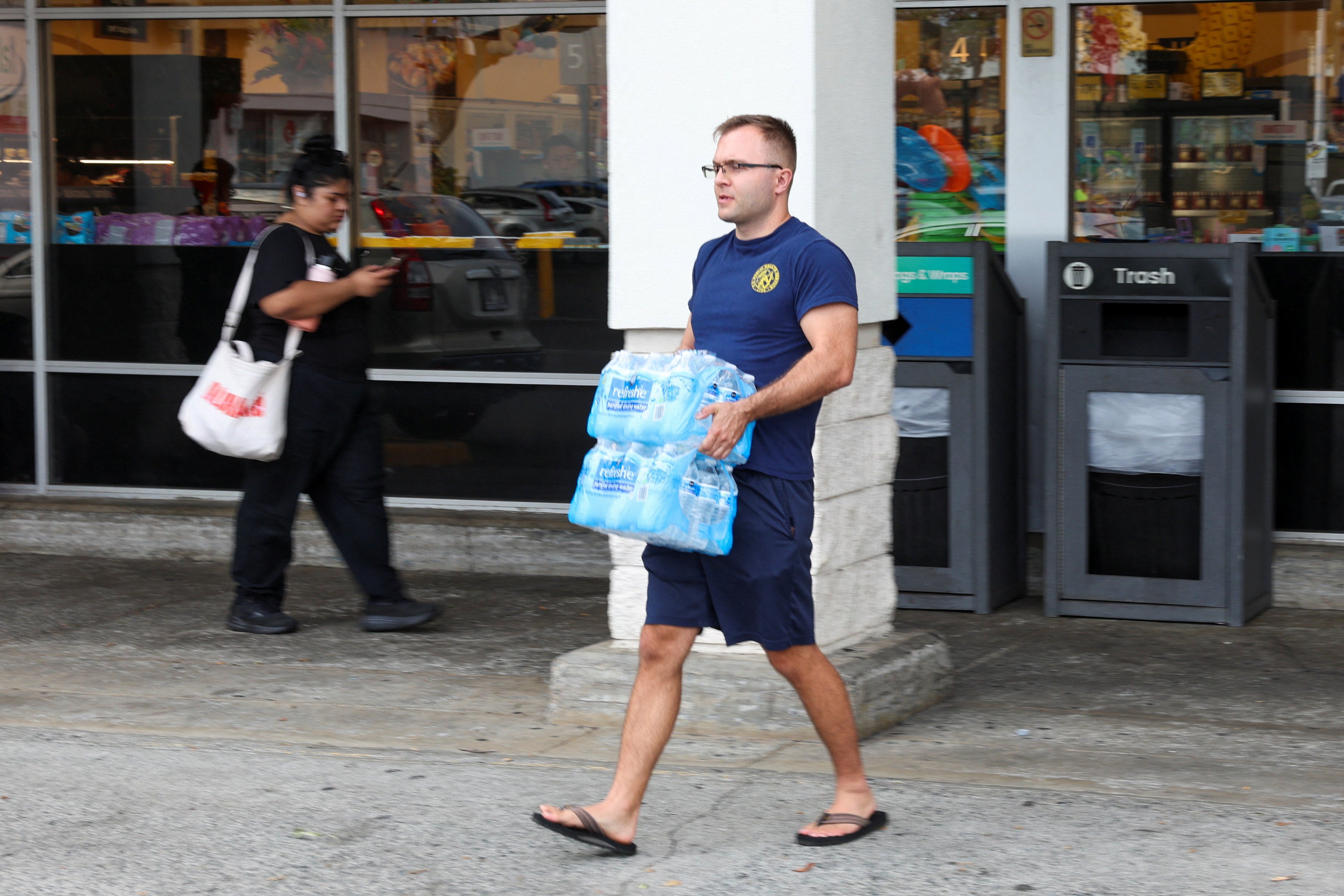 A man carries bottled water out of a grocery store after authorities warned residents of the possibility of destructive tsunami waves in Honolulu, Hawaii