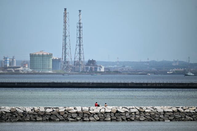 <p>Two people sit out on a breakwater along Tokyo Bay in Chiba City after much of coastal Japan went on tsunami alert following an 8.7-magnitude quake in the sea off eastern Russia</p>