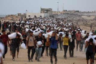 Palestinians carry aid supplies, that entered Gaza on trucks through Israel, in Beit Lahia