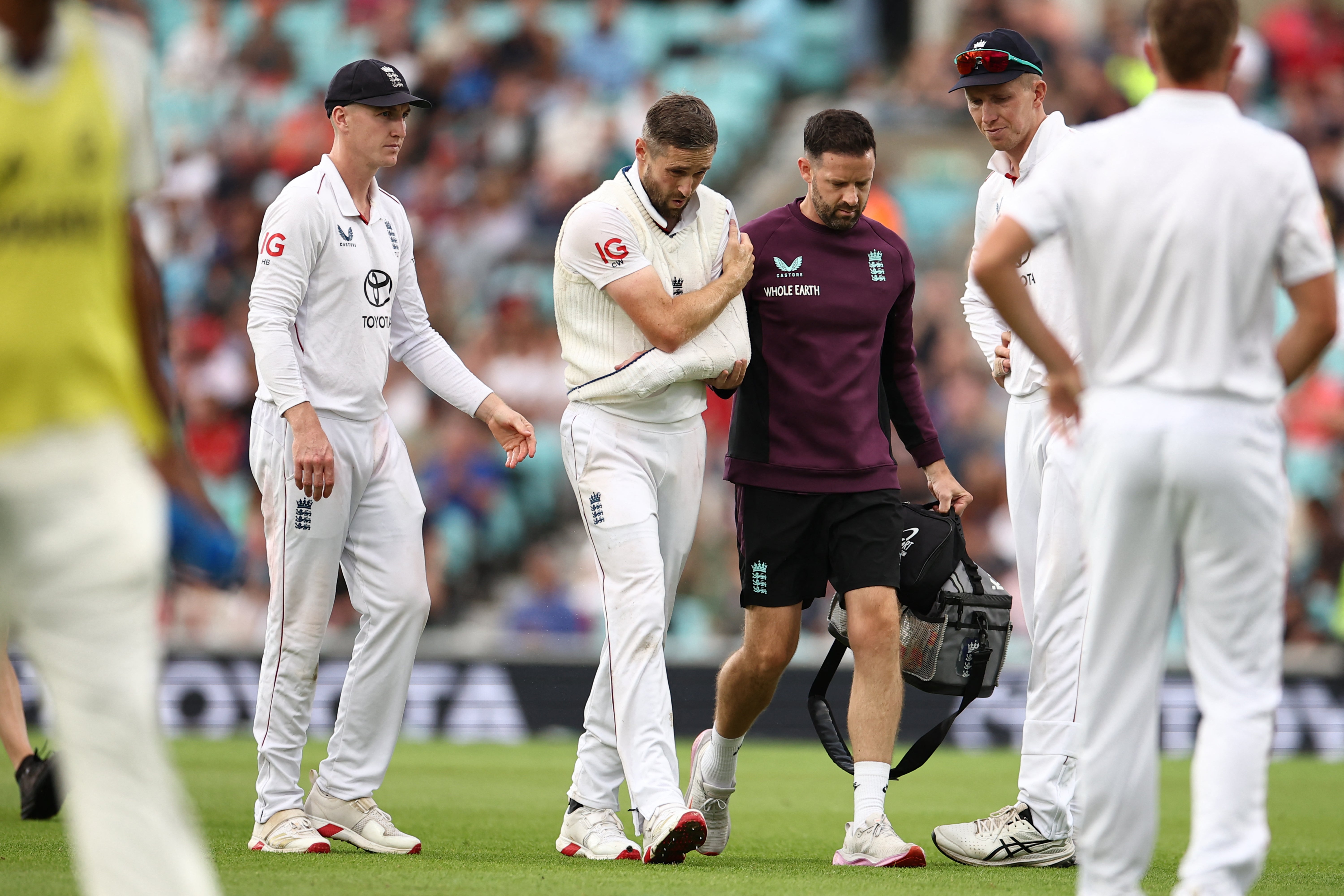 Chris Woakes is led off the field clutching his shoulder
