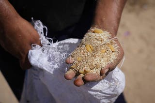 A Palestinian man displays the contents of humanitarian aid packages after they were airdropped into Zawaida, in the central Gaza Strip
