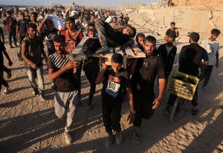 Palestinians carry a person wounded by Israeli fire, as others carry aid supplies that entered Gaza through Israel, in Beit Lahia
