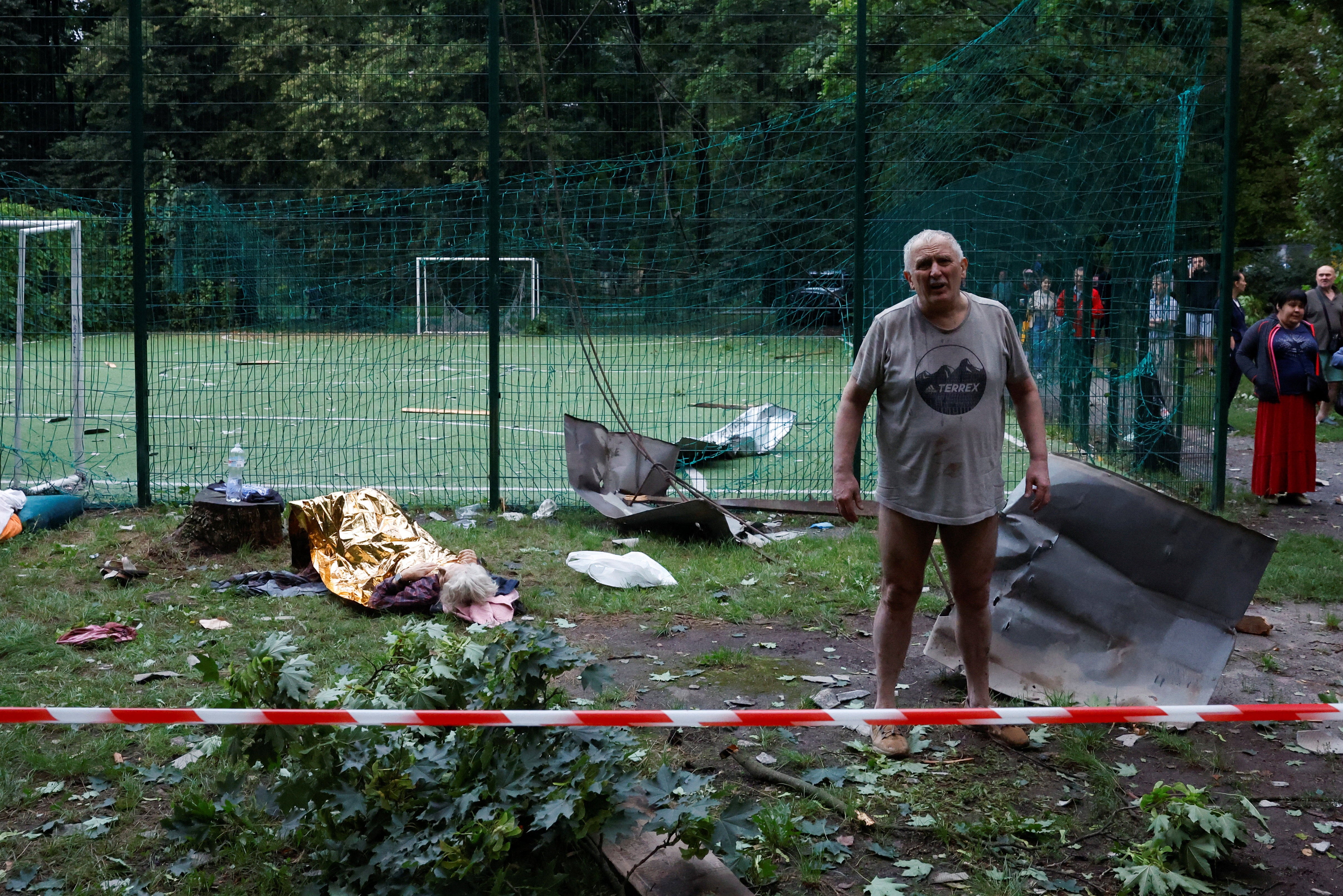 An injured resident stands outside his damaged apartment building hit during Russian missile and drone strikes in Kyiv