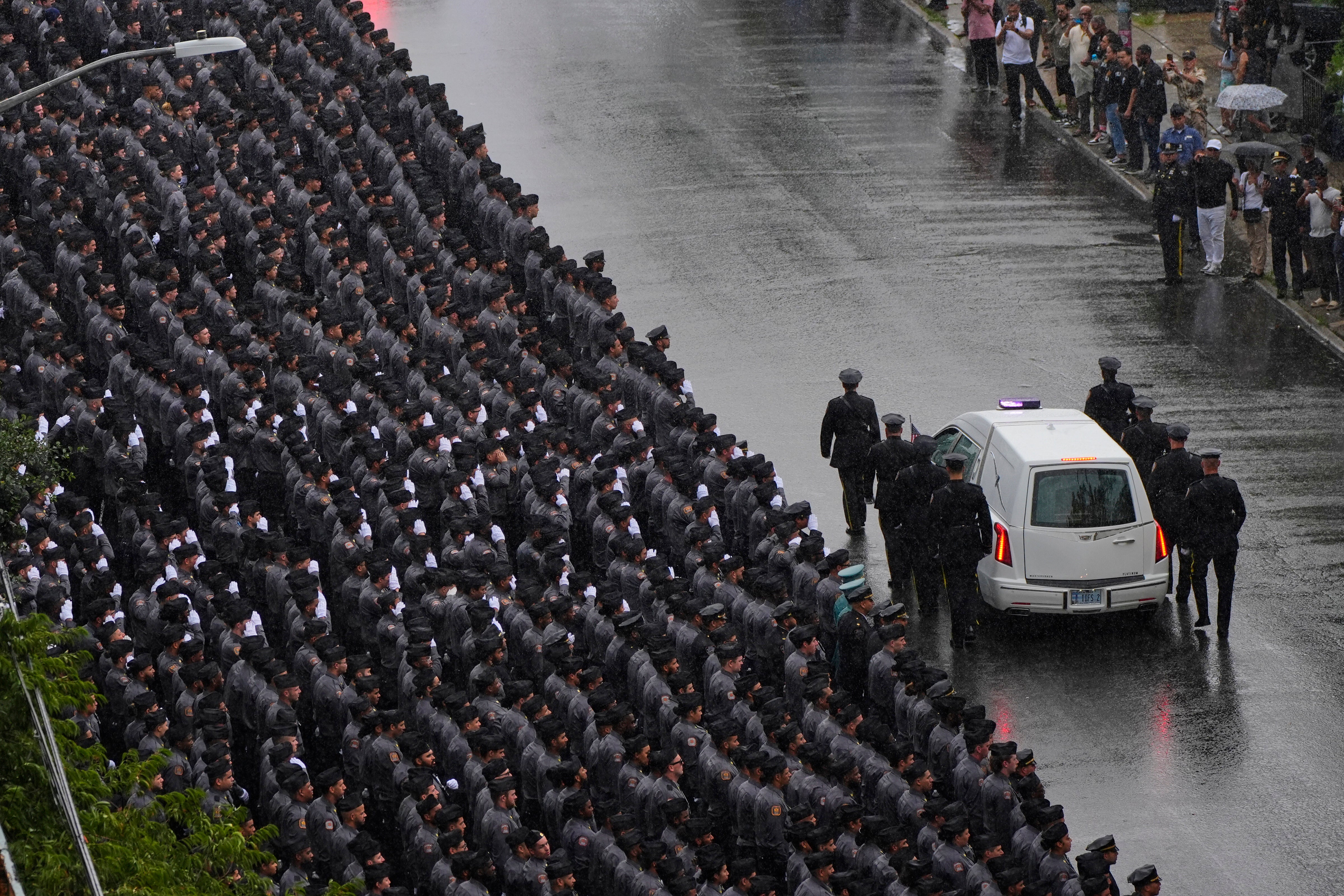 New York Police officers salute as the hearse carries the casket