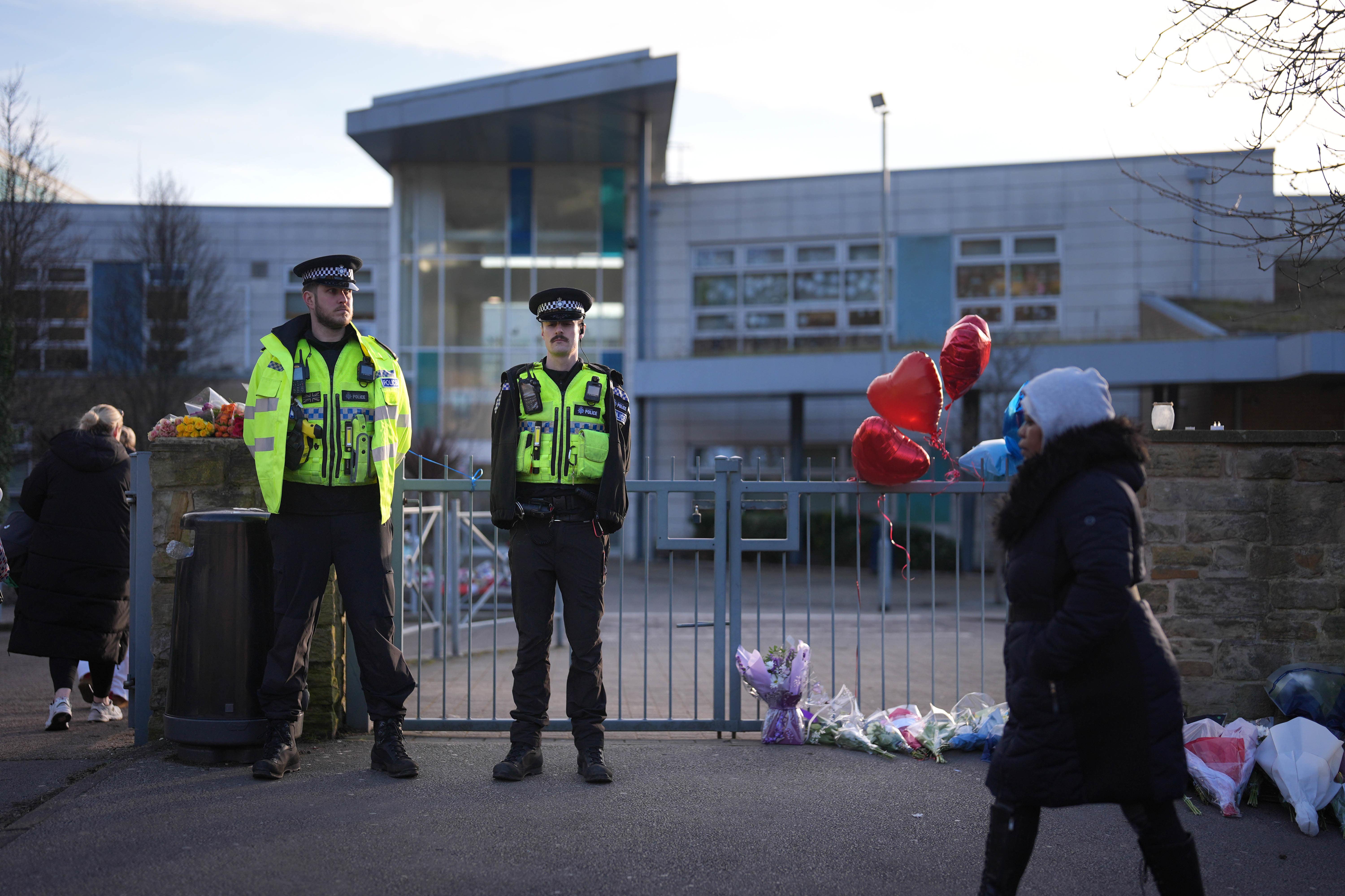 Police officers and floral tributes outside all saints Catholic High School