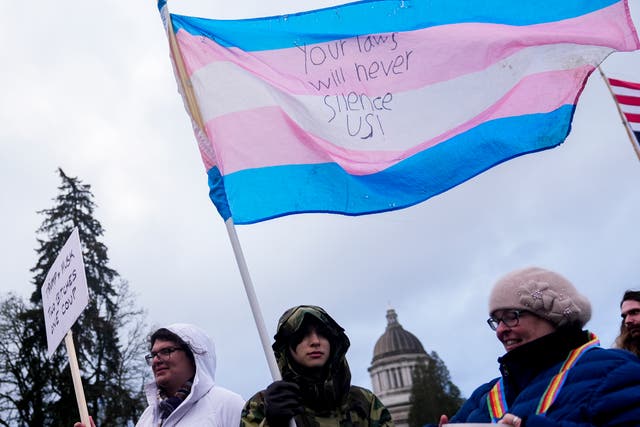 <p>Liv Y., center, holds a transgender pride flag as people gather to protest against the Trump administration and Project 2025 near the Washington State Capitol building</p>