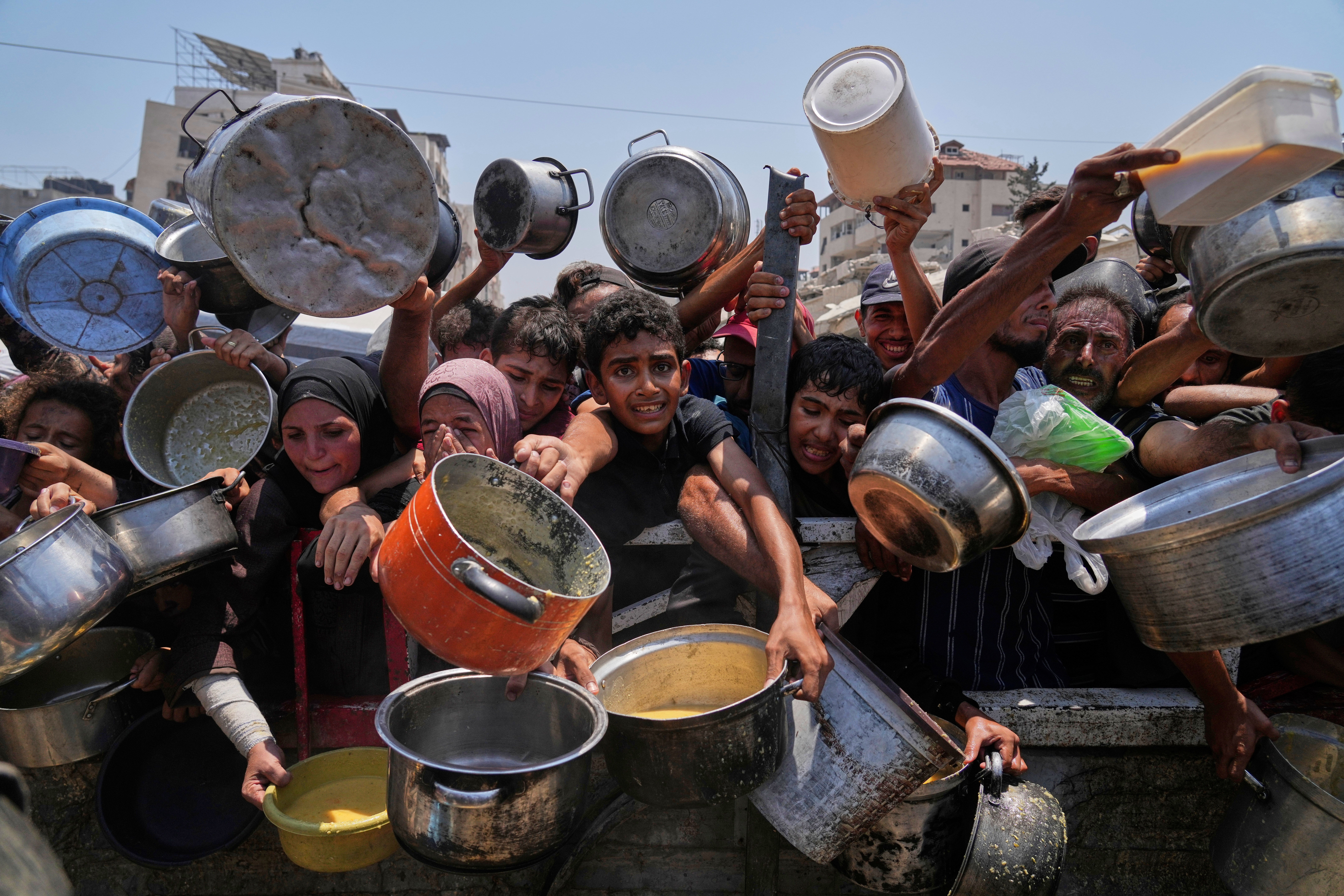 Palestinians struggle to get donated food at a community kitchen in Gaza City, northern Gaza Strip