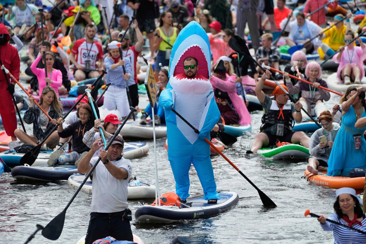 Photos show costumed participants steer stand-up paddle boards at a festival in Russia