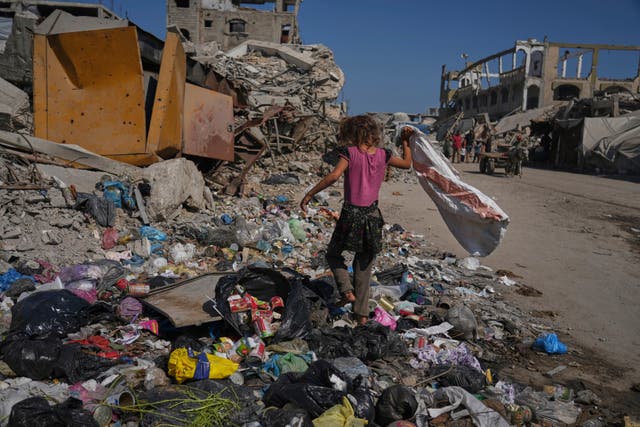 A child searches for plastic to use as cooking fuel next to a makeshift tent camp for displaced Palestinians in Gaza (Jehad Alshrafi/AP/PA)