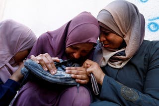 The mother of Mohammed Al-Motawak holds his shoe as his sister and aunt mourn during his funeral