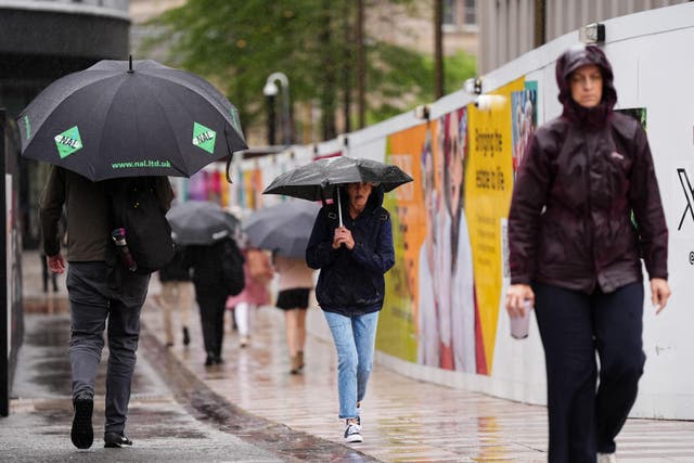 People shield themselves from the rain during Storm Floris (Jacob King/PA)