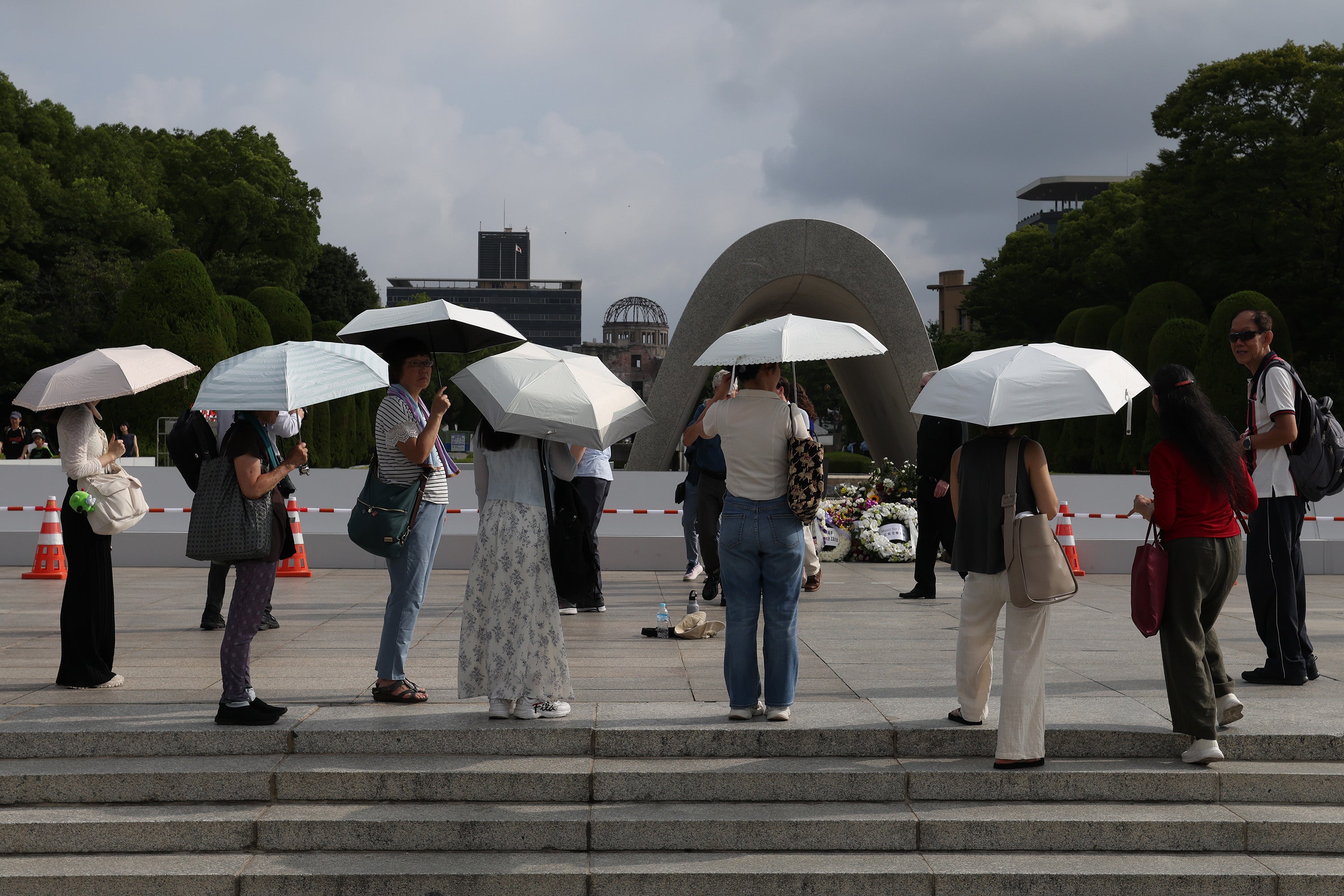 Visitors use umbrellas to get relief from the sun during the extremely hot day ahead of the 80th anniversary of the atomic bomb dropped on Hiroshima at the Hiroshima Peace Memorial on 5 August 2025 in Hiroshima, Japan