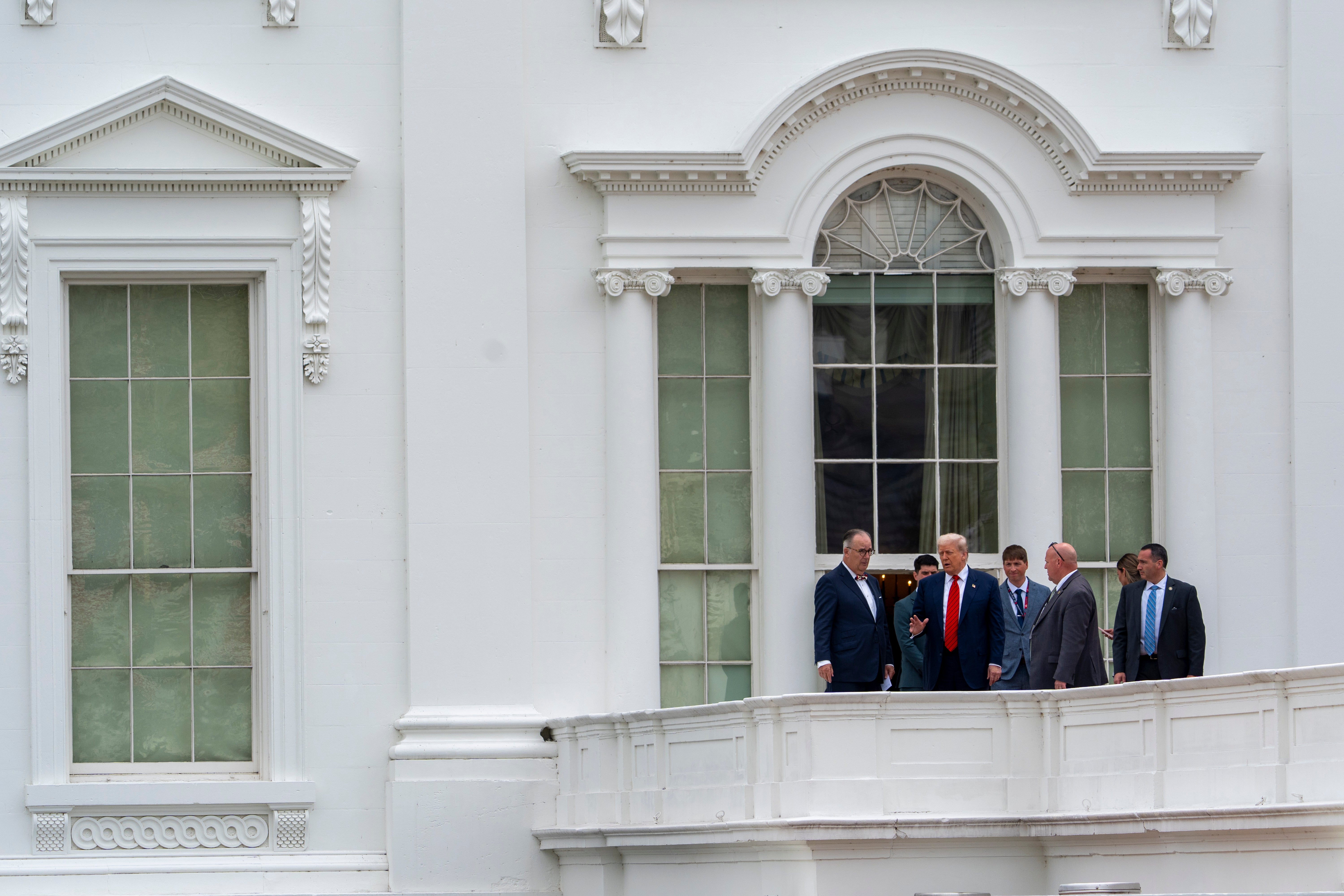 President Donald Trump, with architect James McCrery, left, surveys the grounds from the roof above the Colonnade that goes to the West Wing of the White House.