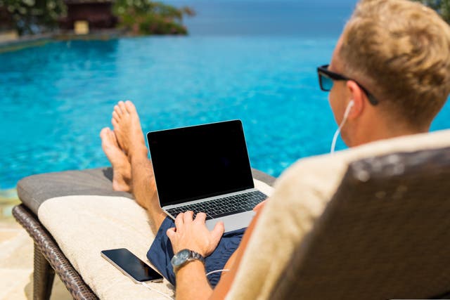 <p>Man using his computer while poolside</p>
