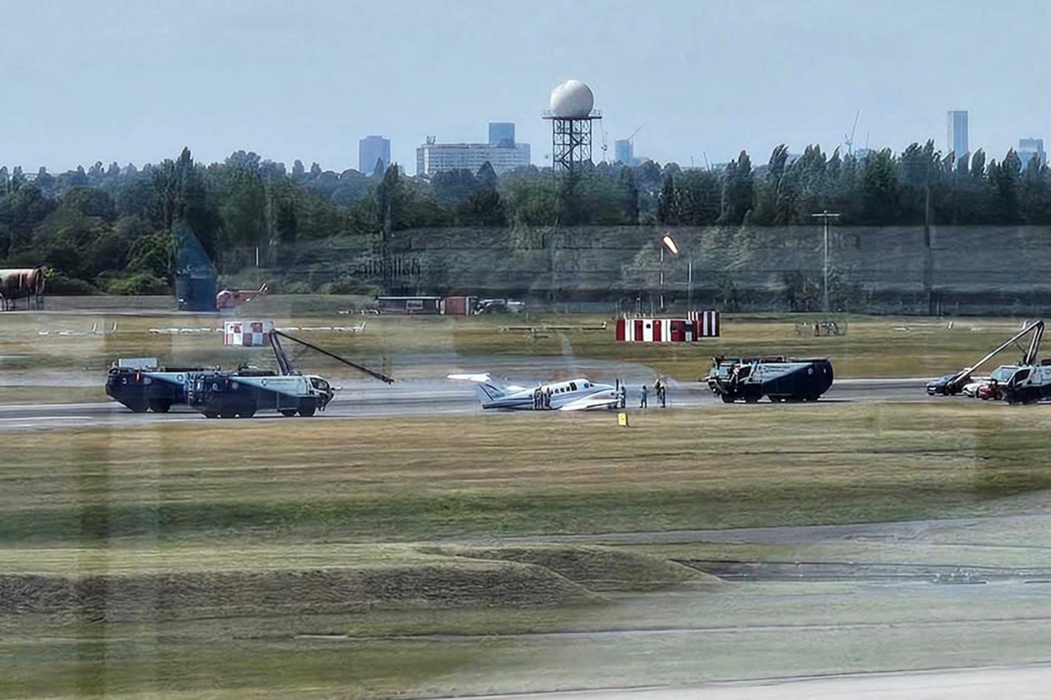 Emergency crews are at the scene near a small propeller plane on the runway