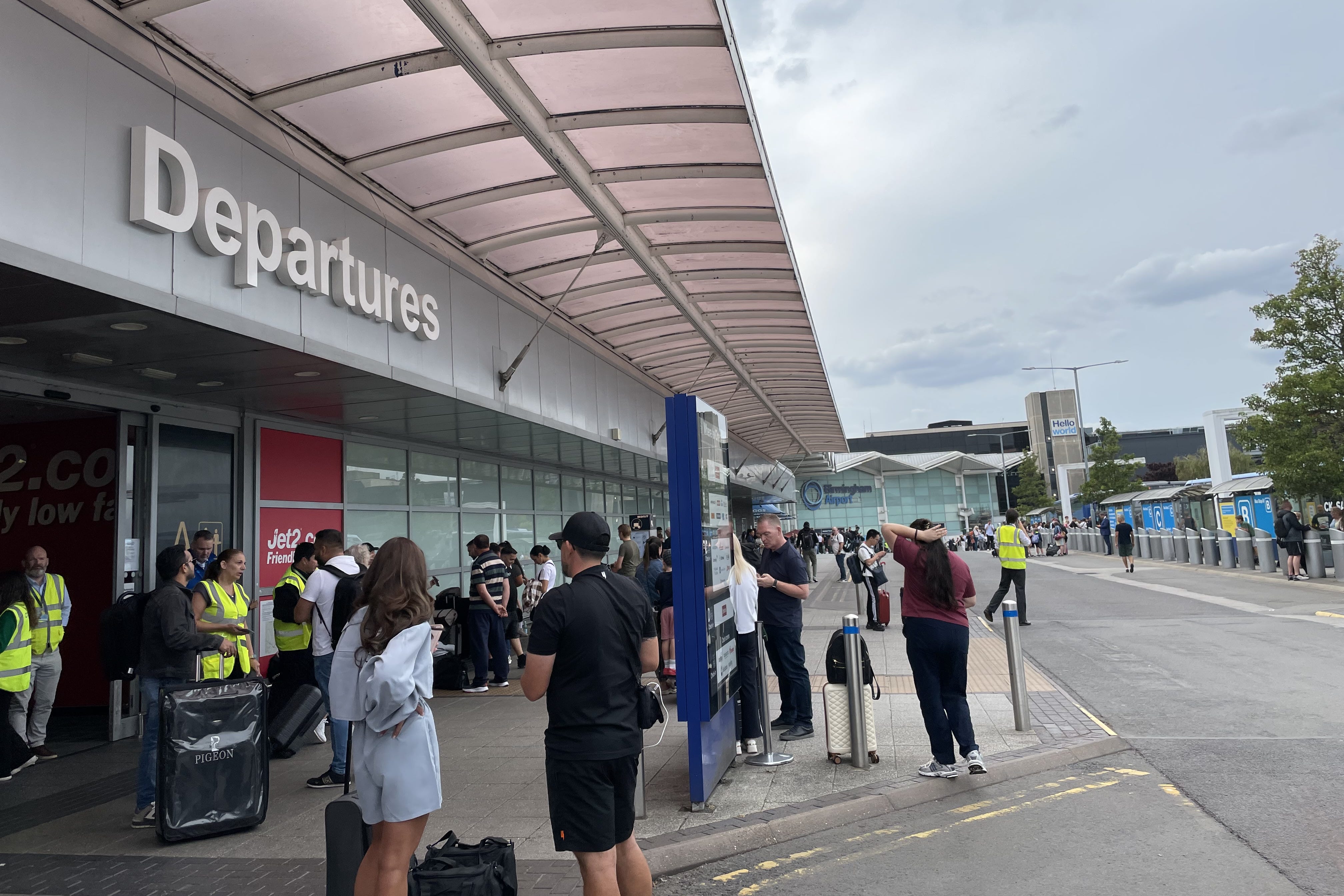 <p>Passengers waiting outside departures at Birmingham Airport </p>