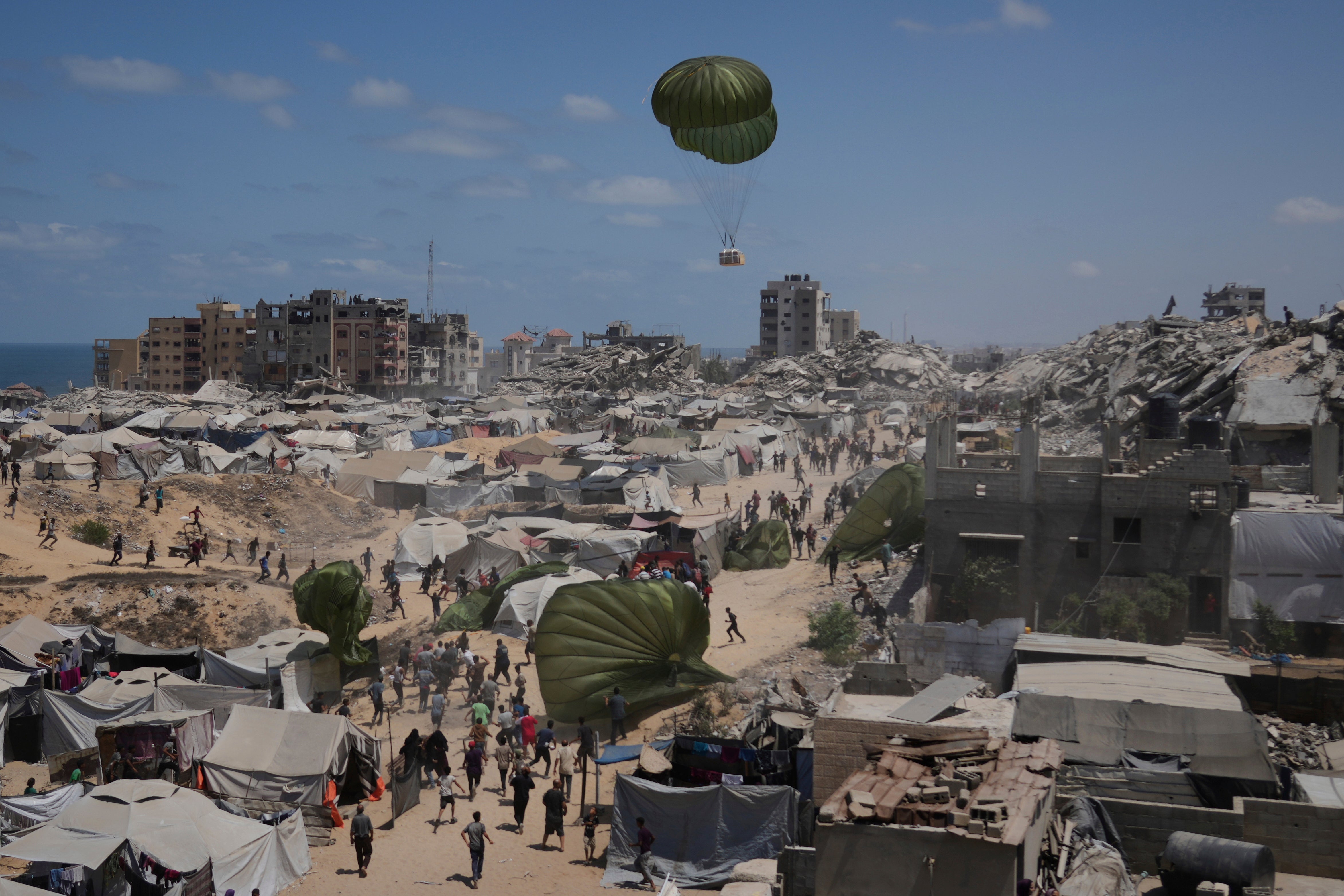 Palestinians rush to collect humanitarian aid airdropped by parachutes into Gaza City