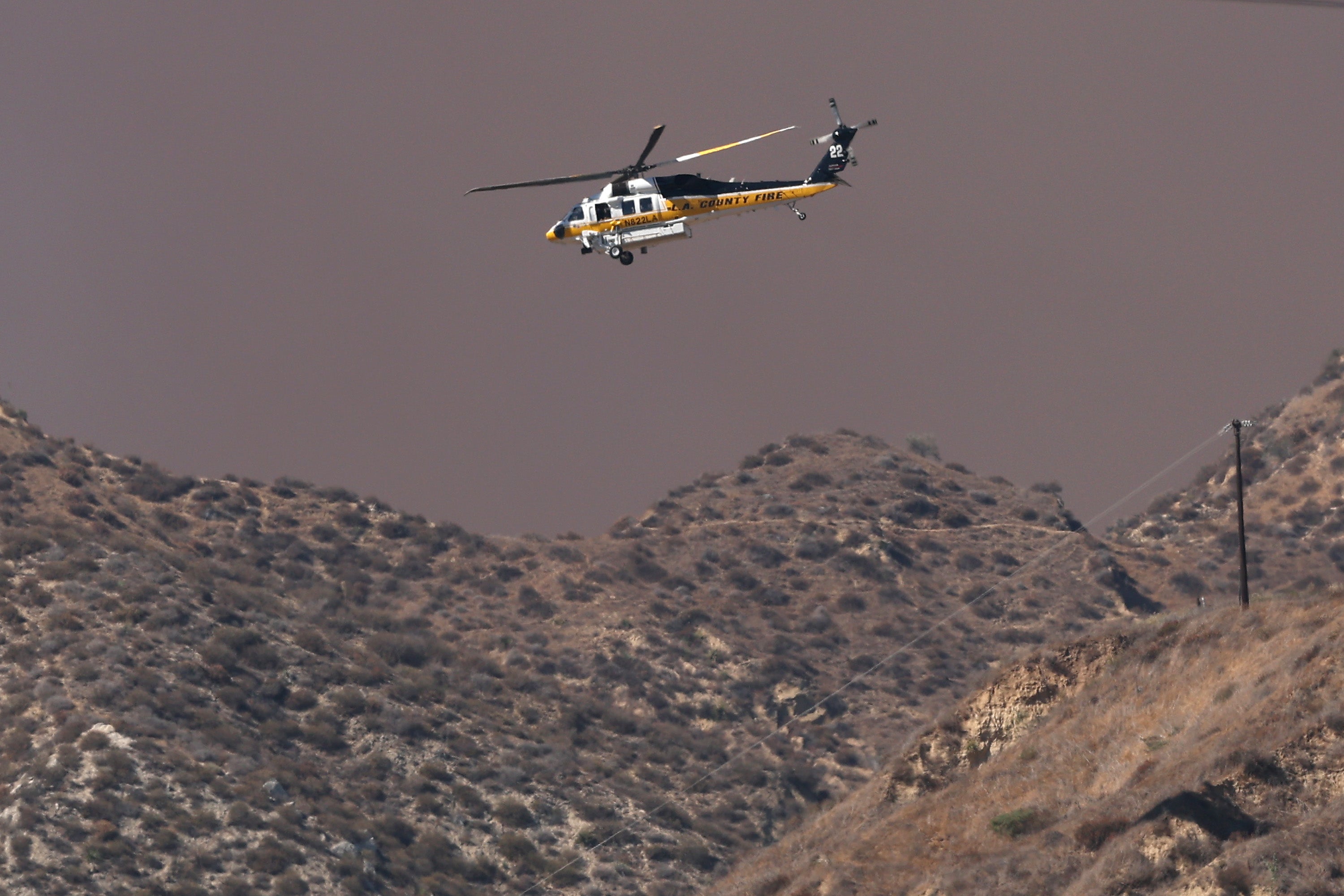 An L.A. County Fire helicopter flies above rising smoke as the Canyon Fire burns on August 7 in Piru, California