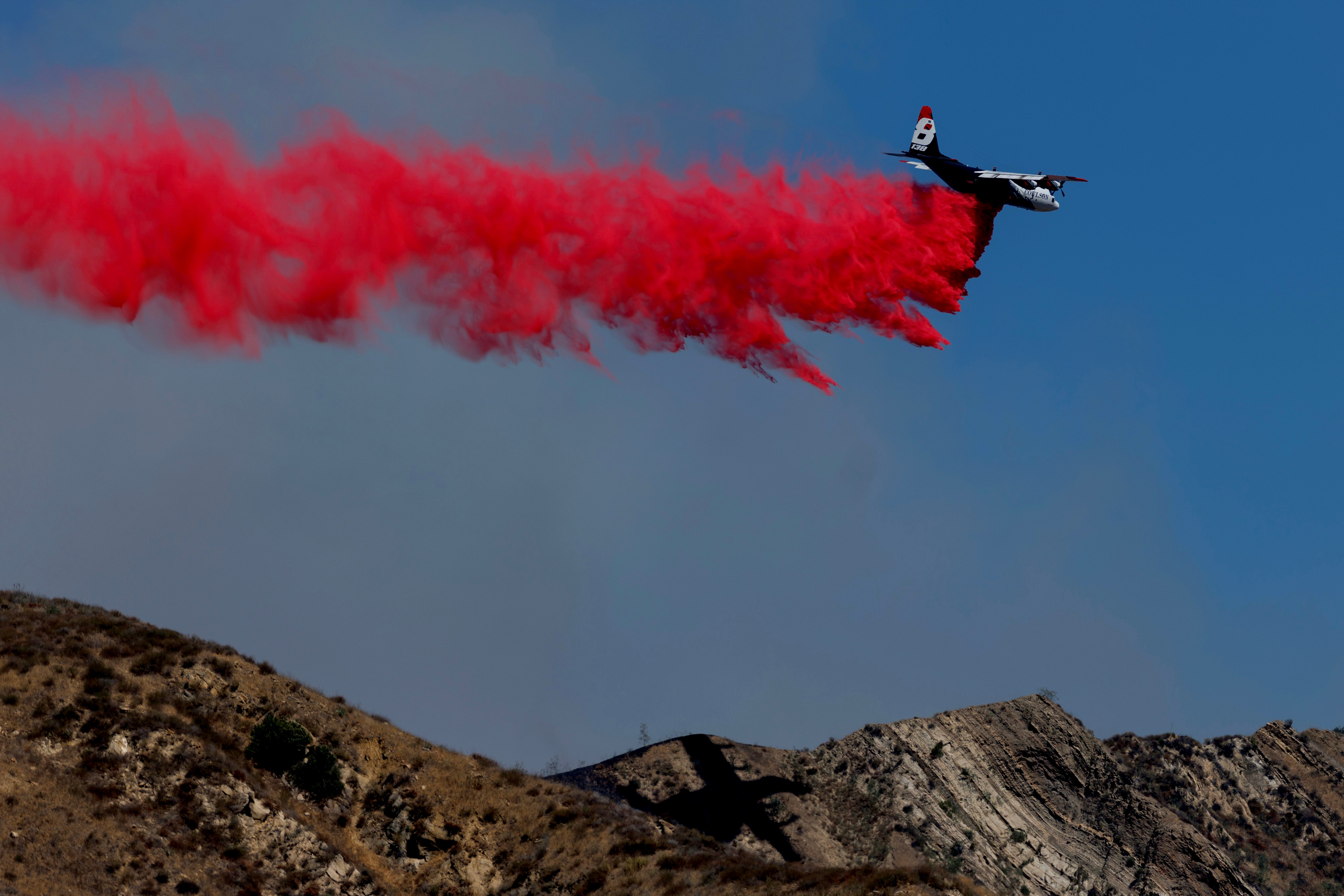A plane drops fire retardant on a hillside during the Canyon Fire on August 7 in Piru, California