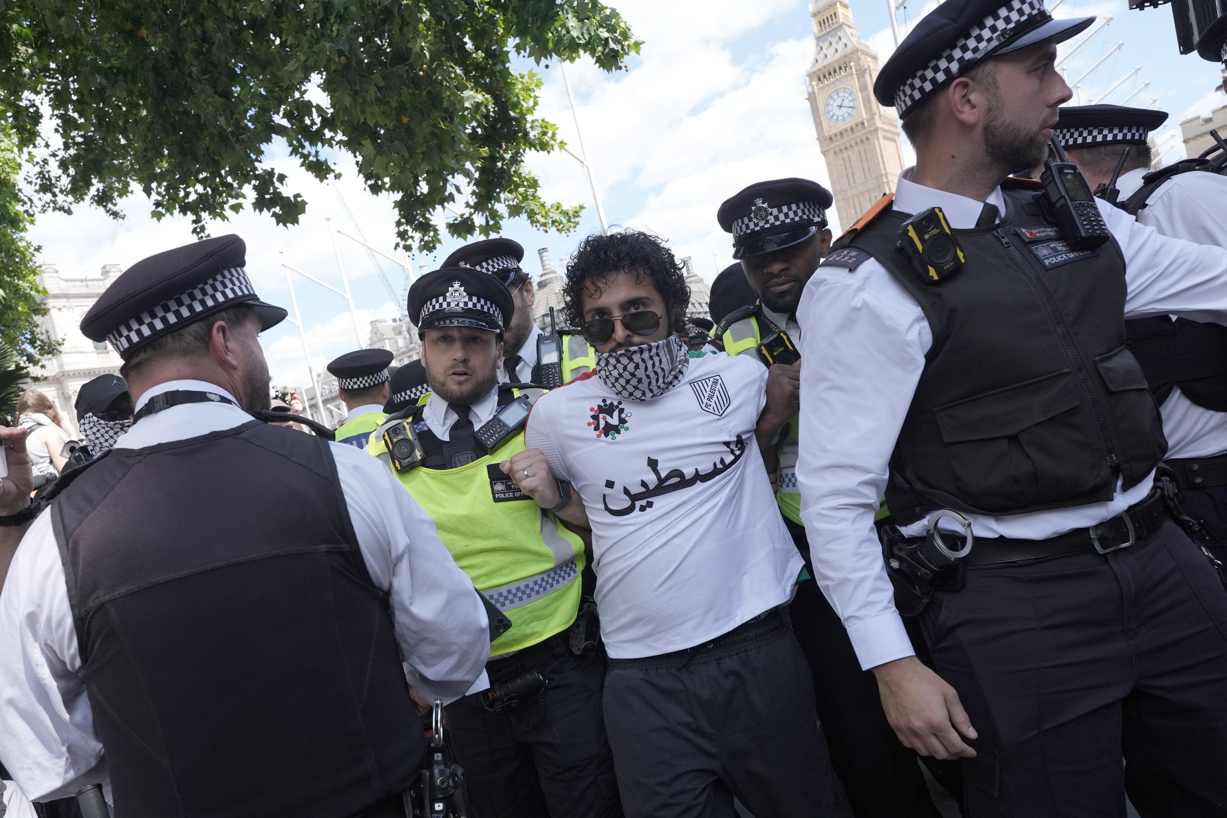 A person is headed by police officers as supporters of Palestine Action participate in a collective action in Parliament Square