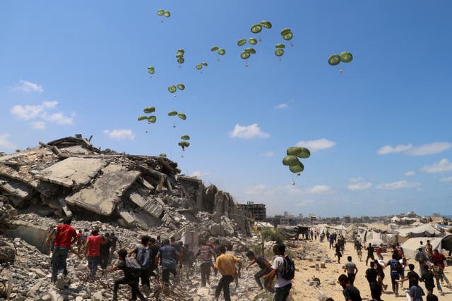 <p>Palestinians run towards parachutes carrying aid packages airdropped over northern Gaza Strip</p>