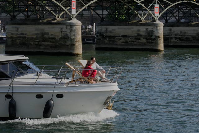<p>People enjoy the sun on a boat on the Seine river in Paris, Sunday, Aug. 10, 2025. (AP Photo/Michel Euler)</p>