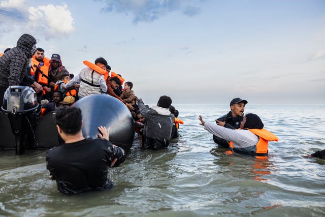 <p>Migrants in northern France try to board a smuggler's boat to cross the English Channel</p>