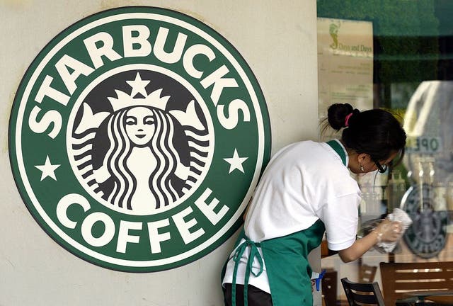 <p>A Starbucks worker cleans the window next to a company logo at a coffee store on 31 May, 2006 in Seoul, South Korea</p>