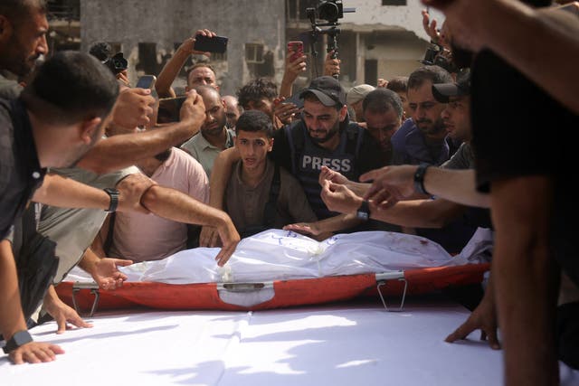 <p> Mourners place the body of Al Jazeera correspondent Anas al-Sharif, who was killed alongside other journalists in an overnight Israeli strike on their tent in Gaza City, on a table ahead of a funeral procession in Gaza City</p>